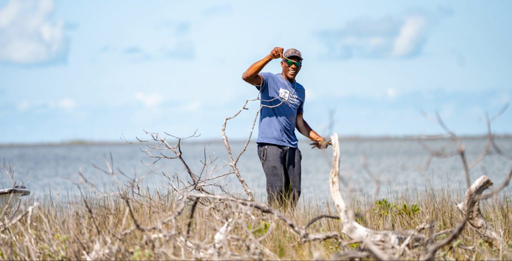 As the afternoon sun bathes the Marls of Abaco in golden light, Bahamian boat captain Willis Levarity–locally known as “Captain to the Stars”–stands ankle-deep in soft, warm mud. A broad smile spreads across his face as he holds up a mangrove propagule, before carefully planting it into the earth. Around him, countless other seedlings sway gently in the breeze—their delicate beginnings a stark contrast to the resilience they promise. This isn't just a landscape on the verge of rebirth; it's a testament to human determination and nature's indomitable spirit in the face of climate adversity.